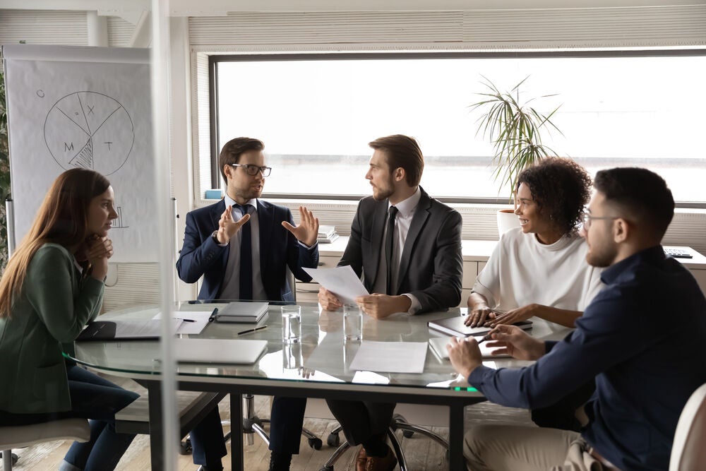 Group of business people sitting around a meeting table discussing graphs