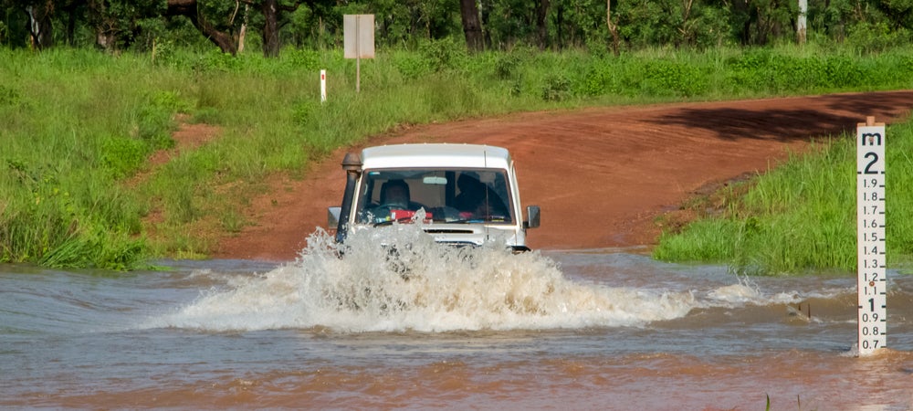 A large Four-Wheel-Drive drives through a flooded road in the Northern Territory.