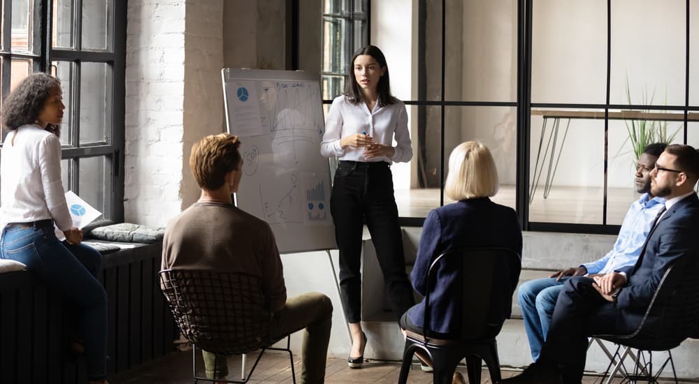 Female CEO presenting a workshop to a group of employees in a modern corporate office.