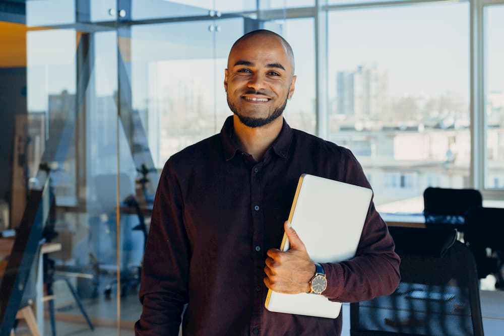 A public health professional smiles and holds a clipboard. 