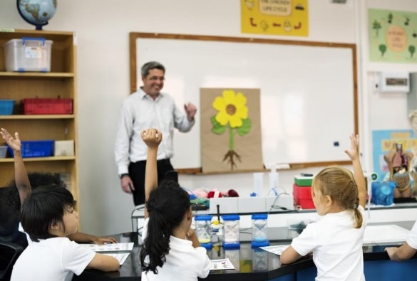 A primary school teacher stands at the front of the classroom.