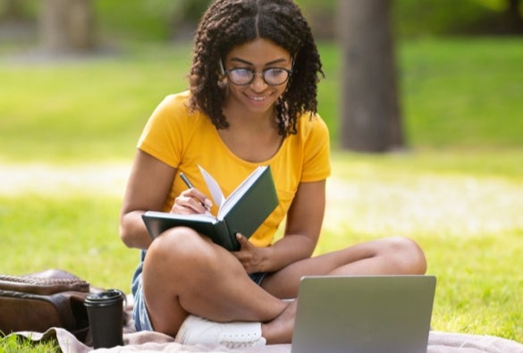 A VU Online student studies outside.