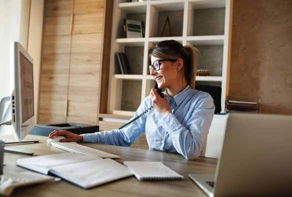 An investment banker busy working on their desk and talking on the phone.