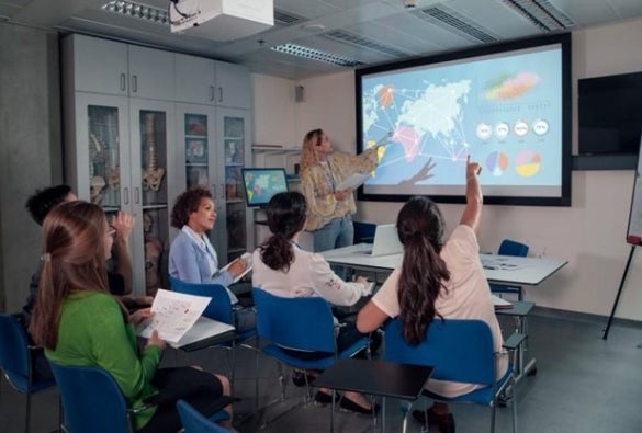 A public health educator gives a presentation on international healthcare using a world map.