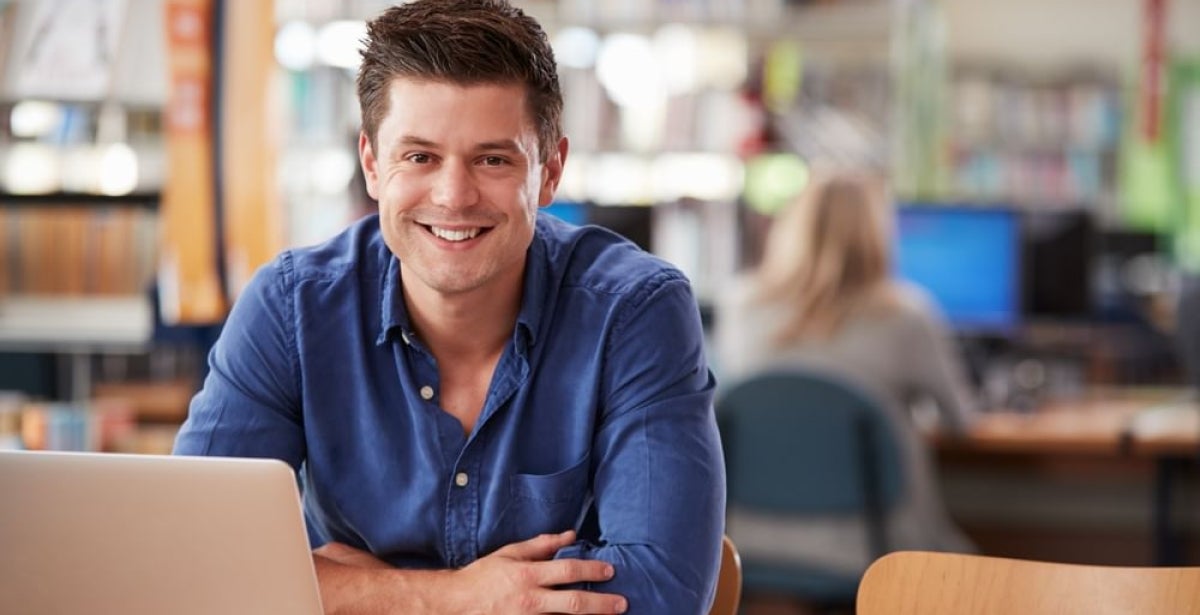 A VU Online Master of Financial Planning student sits smiling at a table with a laptop and documents.