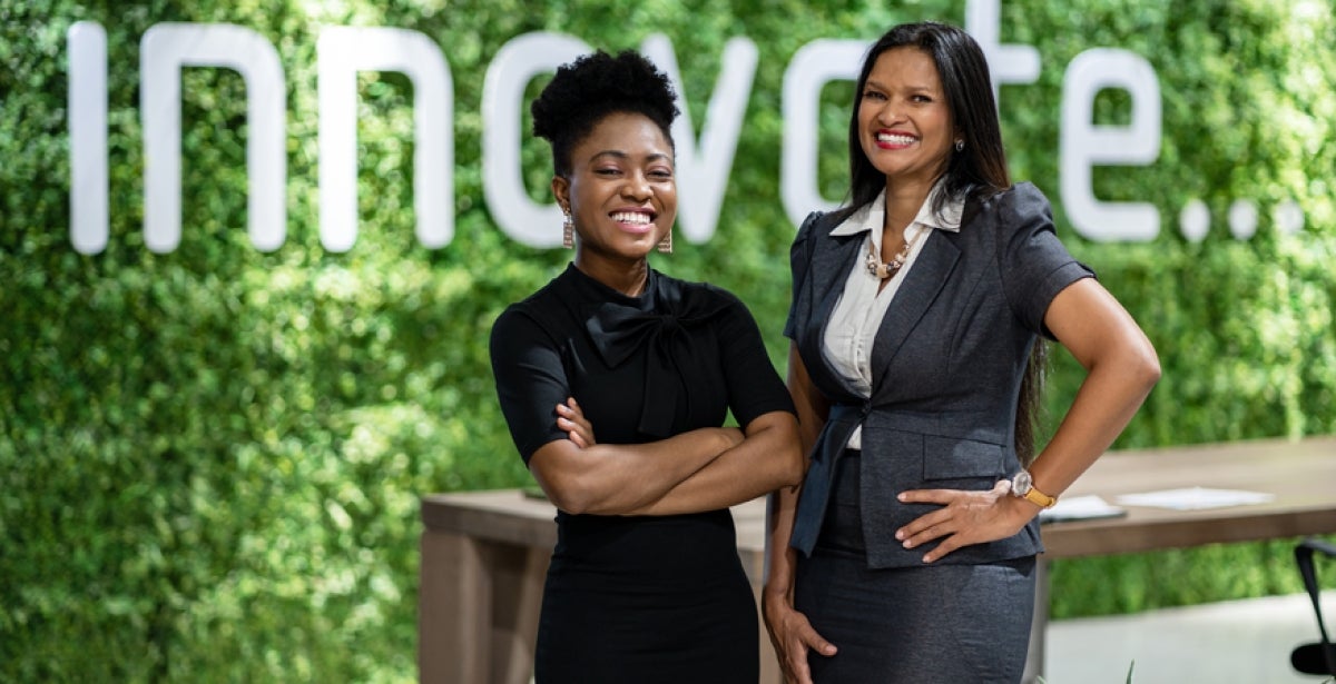 Two business leaders stand in front of a sign that says ‘innovation.’