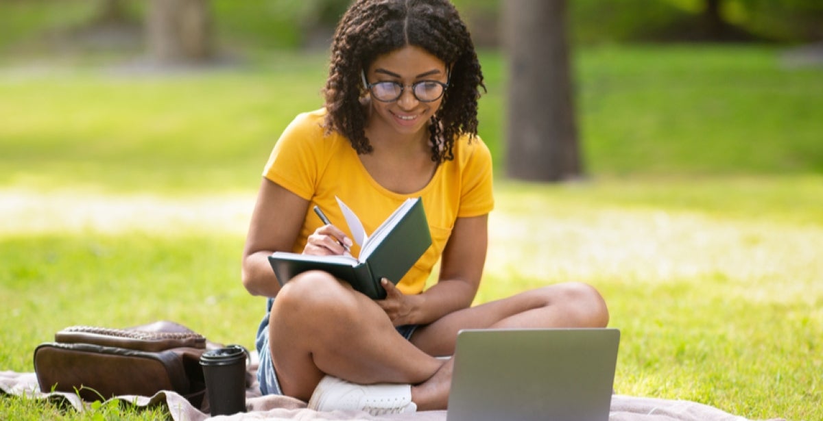 A VU Online student studies outside.