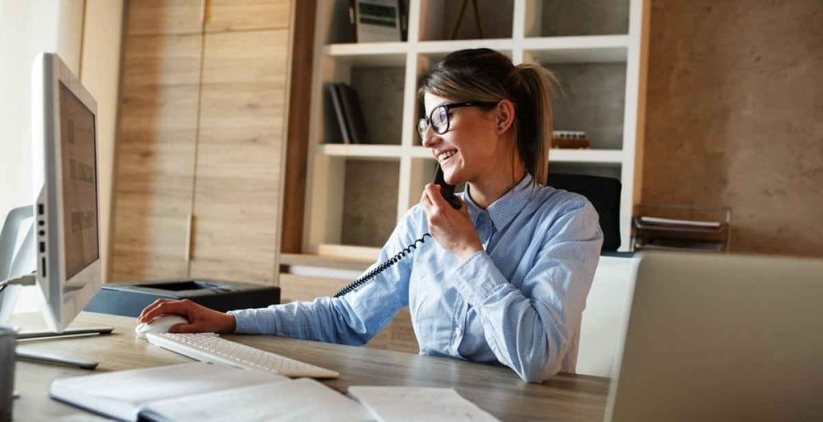 An investment banker busy working on their desk and talking on the phone.