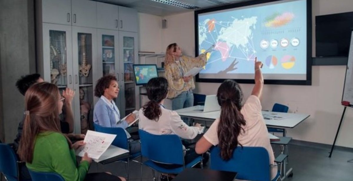 A public health educator gives a presentation on international healthcare using a world map.