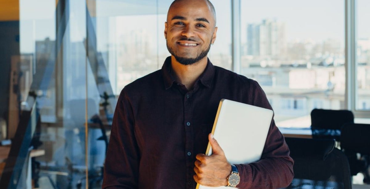 A smiling NGO worker holding a laptop.