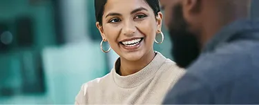 1. A woman smiles at a man in an office setting, conveying a positive and friendly interaction between colleagues.
