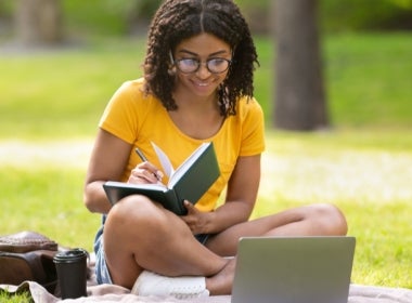 A VU Online student studies outside.