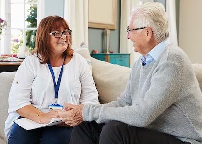 Adult Caucasian female counselor talking with elderly Caucasian male patient