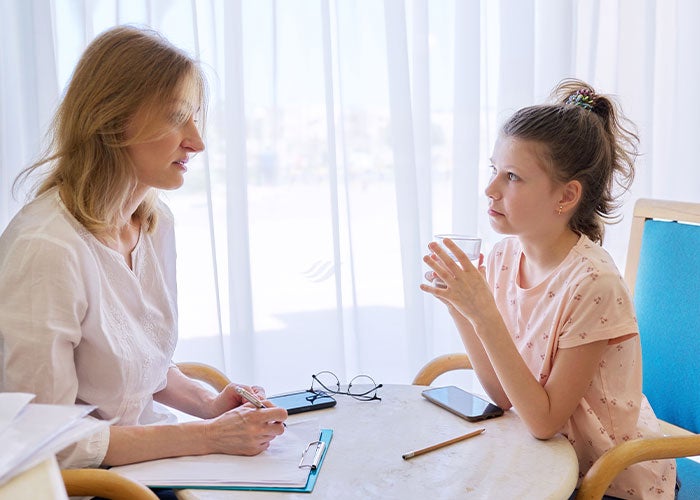 Female Caucasian counsellor sitting and talking to female Caucasian child patient
